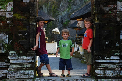 3 children stand at an entrance to an ancient temple courtyard in Bali